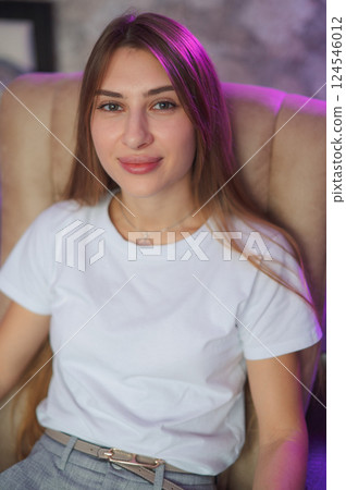 Portrait, young and woman 20s at house with smile to relax in living room as student for break on weekend. Happy, carefree and female person with confident comfort for calm peace in a white T-shirt 124546012