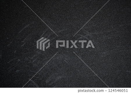 Dark textured surface featuring chalk board residue and scratches, showcasing signs of wear and age, creating a gritty, abstract background 124546051
