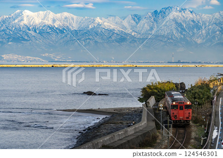 Himi Line train and the Tateyama Mountain Range from the roadside station Amaharashi 124546301