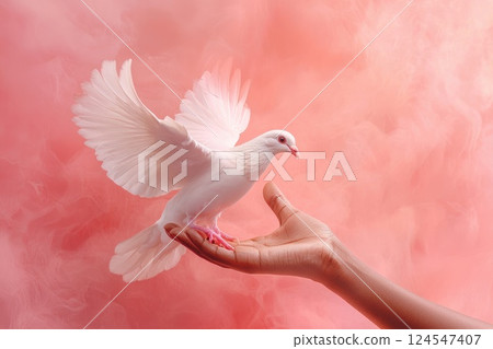 Graceful white dove soaring from a hand amidst a soft pink background, symbolizing peace and freedom in a serene and artistic composition 124547407