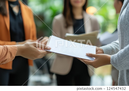 Manager Handing Booklet to Small Team of Employees in Modern Office Setting Manager Handing Booklet to Small Team of Employees in Modern Office Setting 124547432