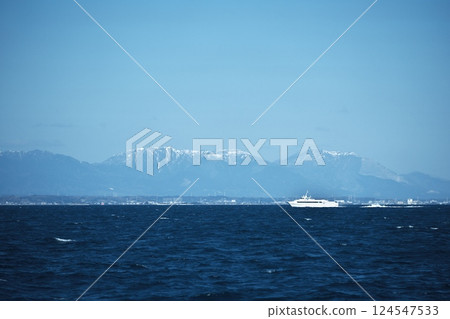 The Tsu Airport Line high-speed ferry races along, raising white waves with the snow-capped mountains in the background. The Tsu Airport Line high-speed ferry races along, raising white waves with the snow-capped mountains in the background. 124547533