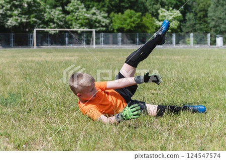Goalkeeper boy falling on grass during soccer save. 124547574