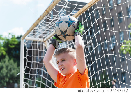 Goalkeeper boy catching soccer ball above his head. 124547582