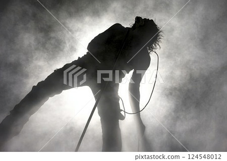 Confident Speaker Standing on Stage in Dramatic Lighting with Microphone in Hand 124548012