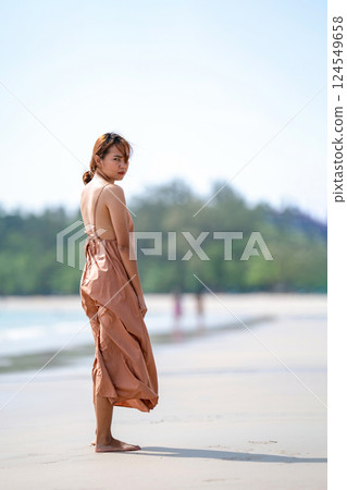 Beautiful Relaxed Thai Woman poses on the beach in the sunlight  with happiness and relaxation. 124549658