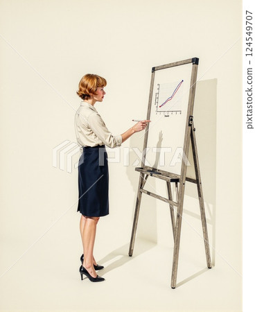 Caucasian female adult presenting on flipchart with rising graph in professional attire 124549707