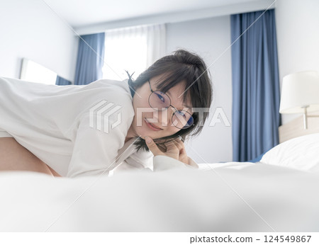 Sexy and cute Japanese, Chinese Thai woman wears white long arm T Shirt on the bed, looks at the camera. 124549867