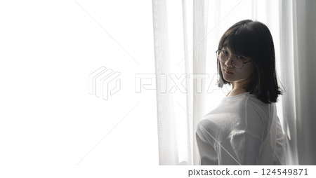 Asian Thai Chinese Woman with her black glasses stands in front of white curtain with the light from outside. It's a cute sexy shot image. 124549871