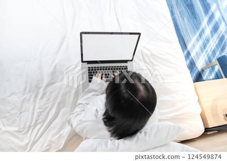 Topview of Glasses Asian cute woman works with laptop white screen on the bed in Work From Home period. Topview of Glasses Asian cute woman works with laptop white screen on the bed in Work From Home period. 124549874