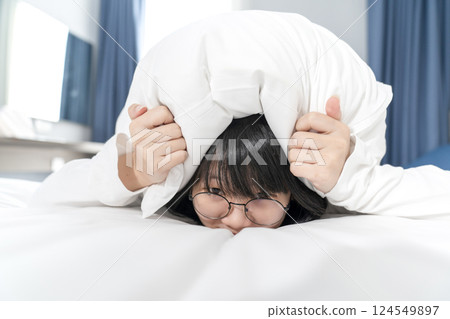 The Asian Pretty glasses woman feels afraid and uncomfortable, she holds white pillow to cover her head on the bed The Asian Pretty glasses woman feels afraid and uncomfortable, she holds white pillow to cover her head on the bed 124549897