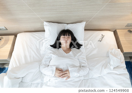 Asian woman sleeps on white bed after exhausted and tried all day. 124549908