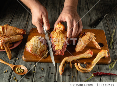 Hands skillfully cut raw poultry parts on a wooden board surrounded by spices and herbs in a cozy kitchen filled with natural light Hands skillfully cut raw poultry parts on a wooden board surrounded by spices and herbs in a cozy kitchen filled with natural light 124550645