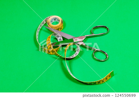 Tape measure and sharp tailor's scissors, placed on the table. Tape measure and sharp tailor's scissors, placed on the table. 124550699