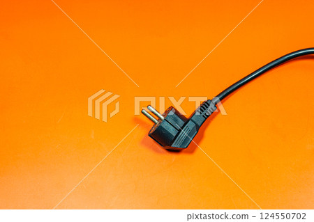 Black plug cable on an orange surface. 124550702