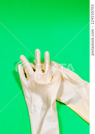White rubber gloves on a green surface. 124550703