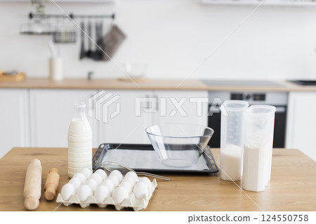 Ingredients and utensils arranged for baking preparation in a modern white kitchen setting 124550758
