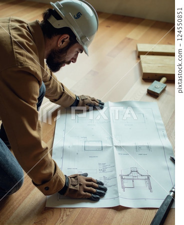 Architect examining blueprints on wooden floor for construction planning 124550851