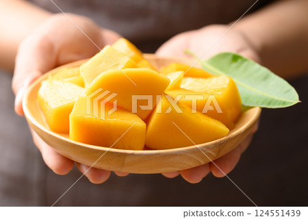 Cube mango on wooden plate holding by hand ready to eating, Tropical fruit in summer season Cube mango on wooden plate holding by hand ready to eating, Tropical fruit in summer season 124551439
