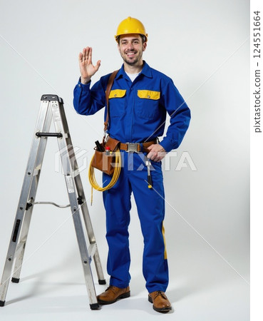 Friendly construction worker waves beside ladder in blue uniform for safety promotion or project design 124551664