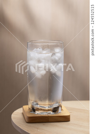 Cold water fills a glass, ice cubes floating within. Cold water fills a glass, ice cubes floating within. 124552515