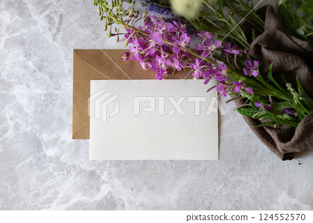 Handmade stationery with purple flowers and a brown envelope on a marble surface creating an inviting workspace atmosphere Handmade stationery with purple flowers and a brown envelope on a marble surface creating an inviting workspace atmosphere 124552570