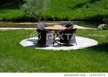 Outdoor seating area with wicker and metal furniture on lush green lawn. 124552571