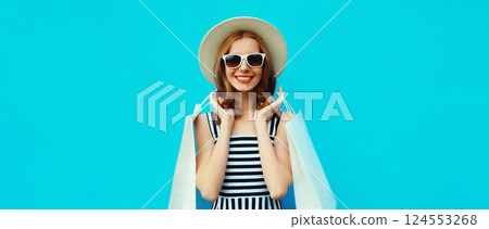 Stylish beautiful happy smiling young woman with shopping bags wearing summer hat on blue background Stylish beautiful happy smiling young woman with shopping bags wearing summer hat on blue background 124553268