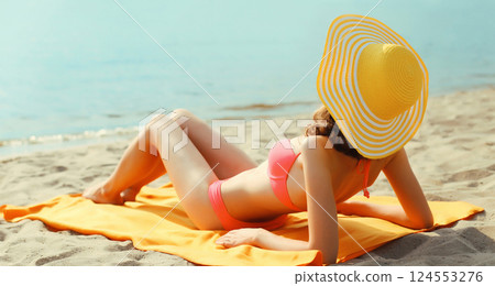 Summer vacation, beautiful happy relaxing young woman with tourist hat lying on the beach at sea 124553276