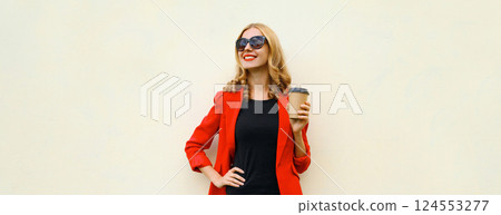 Stylish happy woman in red business suit with cup of coffee looking away stands on white background 124553277
