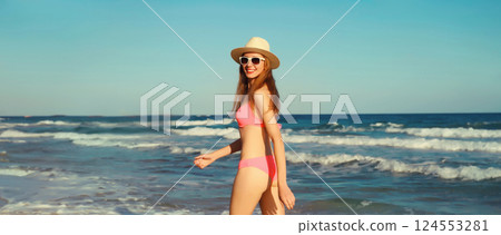 Summer vacation, happy young woman walking running in bikini, tourist hat on the beach on sea coast Summer vacation, happy young woman walking running in bikini, tourist hat on the beach on sea coast 124553281
