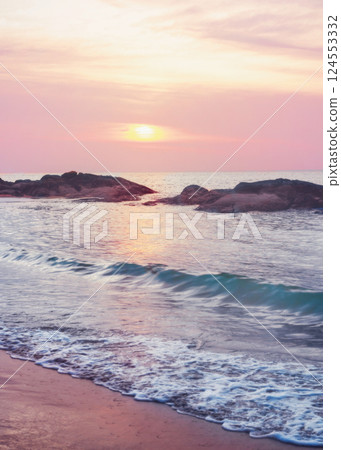 ailand - Turquoise waves of the sea wash over the sandy beach. Stones are visible in the water - a feature of the beaches of Khao Lak in Thailand. 124553332