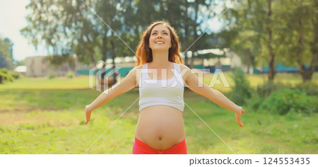 Happy young pregnant woman enjoying warm sunny day in summer park 124553435