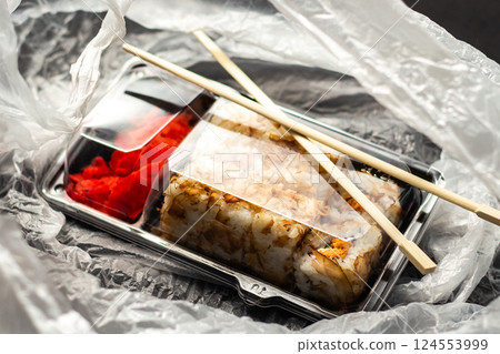 Sushi roll set in take away package in delivery bag. Food delivery concept. Food in plastic packaging Sushi roll set in take away package in delivery bag. Food delivery concept. Food in plastic packaging 124553999
