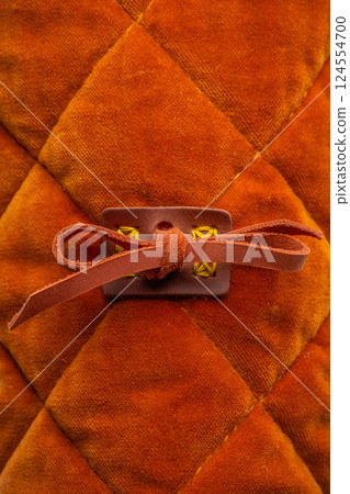 Close-up of Gambeson Sleeve Tie. Detailed view of the fabric and leather tie used to fasten the sleeve of a medieval gambeson. 124554700