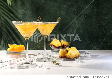 Lemonade royal cocktail, martini or punch of tequila, rum and vodka with pineapple slices, orange, ice and rosemary. Summer party concept. Diet drink for bar or cafe advertising, restaurant menu 124554741