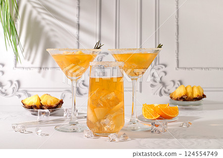 Summer party concept. Lemonade royal cocktail, martini or punch made of tequila, rum and vodka with pineapple slices, orange, ice and rosemary. Diet drink for bar or cafe advertising, restaurant menu 124554749