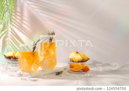 Tequila, rum and vodka cocktail with pineapple slices, orange, ice and rosemary. Summer party concept. Diet drink for detoxification and weight loss, bar or cafe advertisement, restaurant menu 124554750