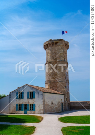 Stone watchtower with blue shutters and a French flag waving on top 124554805