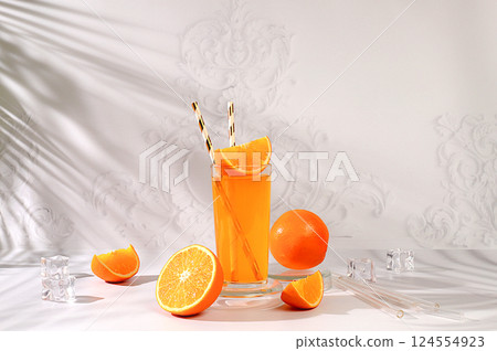 Modern still life with citrus fruits, Orange juice and oranges on elegant kitchen table with long hard shadows. minimal detox diet concept, summer vitamin drinks, selective focus, space for text 124554923
