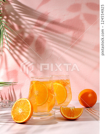 Orange juice and oranges on elegant kitchen table with long hard shadows. Modern still life with citrus fruits, minimal detox diet concept, summer vitamin drinks, selective focus, space for text 124554925