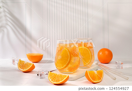 Modern still life with citrus fruits, Orange juice and oranges on elegant kitchen table with long hard shadows. minimal detox diet concept, summer vitamin drinks, selective focus, space for text Modern still life with citrus fruits, Orange juice and oranges on elegant kitchen table with long hard shadows. minimal detox diet concept, summer vitamin drinks, selective focus, space for text 124554927