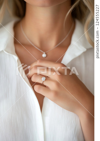 Elegant woman showcasing diamond necklace matching sparkling engagement ring. Close-up of elegance, sparkling jewelry including necklace and a diamond ring. Luxury jewelry 124555227