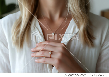 Elegant woman showcasing diamond necklace matching sparkling engagement ring. Close-up of elegance, sparkling jewelry including necklace and a diamond ring. Luxury jewelry 124555228