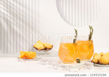 Cold homemade cocktail or lemonade with rosemary, orange, ice and pineapple on a sunny table, Detox diet and summer party concept. Refreshing summer diet drink recipe, restaurant menu, selective Cold homemade cocktail or lemonade with rosemary, orange, ice and pineapple on a sunny table, Detox diet and summer party concept. Refreshing summer diet drink recipe, restaurant menu, selective 124555294
