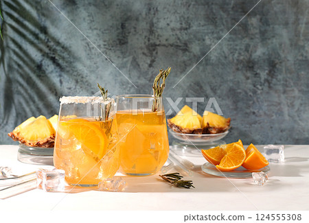 Detox diet and summer party concept. Cold homemade cocktail or lemonade with rosemary, orange, ice and pineapple, Refreshing summer diet drink recipe, restaurant menu, selective approach. Detox diet and summer party concept. Cold homemade cocktail or lemonade with rosemary, orange, ice and pineapple, Refreshing summer diet drink recipe, restaurant menu, selective approach. 124555308
