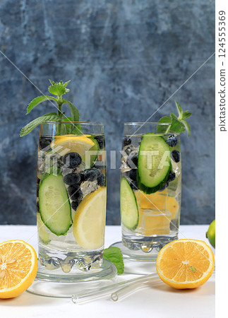 Cold homemade lemonade or cocktail with mint, lemon, cucumber and lime on a sunny table, Detox diet and summer party concept. Refreshing summer drink recipe, restaurant menu, selective approach. Cold homemade lemonade or cocktail with mint, lemon, cucumber and lime on a sunny table, Detox diet and summer party concept. Refreshing summer drink recipe, restaurant menu, selective approach. 124555369