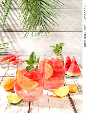 Ice cold homemade lemonade or cocktail with mint, watermelon and fruits on a sunny table, refreshing summer drink recipe, detox diet and weight loss concept, menu for restaurant, selective focus Ice cold homemade lemonade or cocktail with mint, watermelon and fruits on a sunny table, refreshing summer drink recipe, detox diet and weight loss concept, menu for restaurant, selective focus 124555370