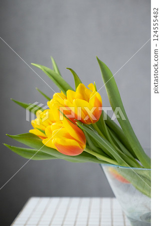 yellow tulips with green leaves lie in glass vase. florist, flower shop. bouquet of flowers. yellow tulips with green leaves lie in glass vase. florist, flower shop. bouquet of flowers. 124555482