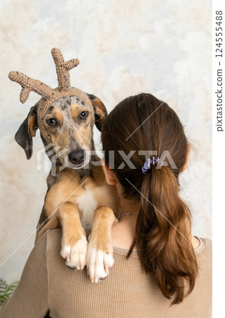 woman holds dog with deer antlers on her head. pet is a spotted grey-brown greyhound. love.  124555488